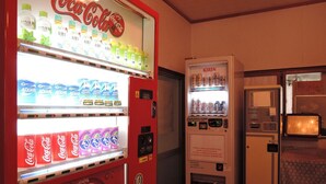 A vending machine with Coca-Cola and Kirin beverages, a refrigerator, and a microwave in a room with wooden flooring. - Shintaku Sanso (Minamimaki)
