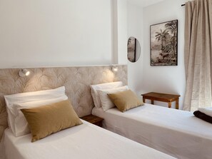 Habitación de hotel con dos camas individuales, una mesita de noche de madera, una mesita pequeña y un espejo fijado a la pared.