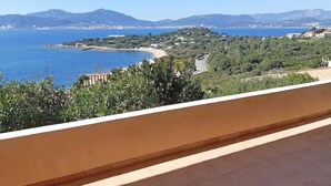 A balcony with a view of a coastal landscape, including a beach and distant mountains. - T3 of 68 m2 in Porticcio. Covered terrace 20 m2, small garden 50 m2. Walking distance to the beach. (Grosseto-Prugna)