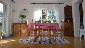 A dining area with a table set for four, a wooden cabinet, and a window with curtains. - Family-friendly, Black Forest Nature Park Murg Valley Baden Baden Hiking vacation  (Weisenbach)