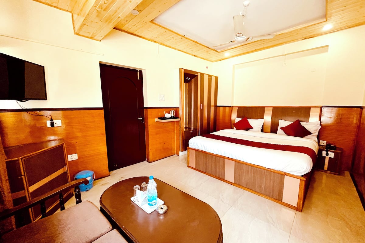 A hotel room with a bed, a desk, a chair, a television, and a ceiling fan.