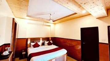 A bedroom with a wooden ceiling, a bed with red and white bedding, a nightstand, and a wardrobe.
