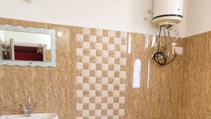 Une salle de bain équipée d’un lavabo, de toilettes et d’un chauffe-eau fixé au mur.