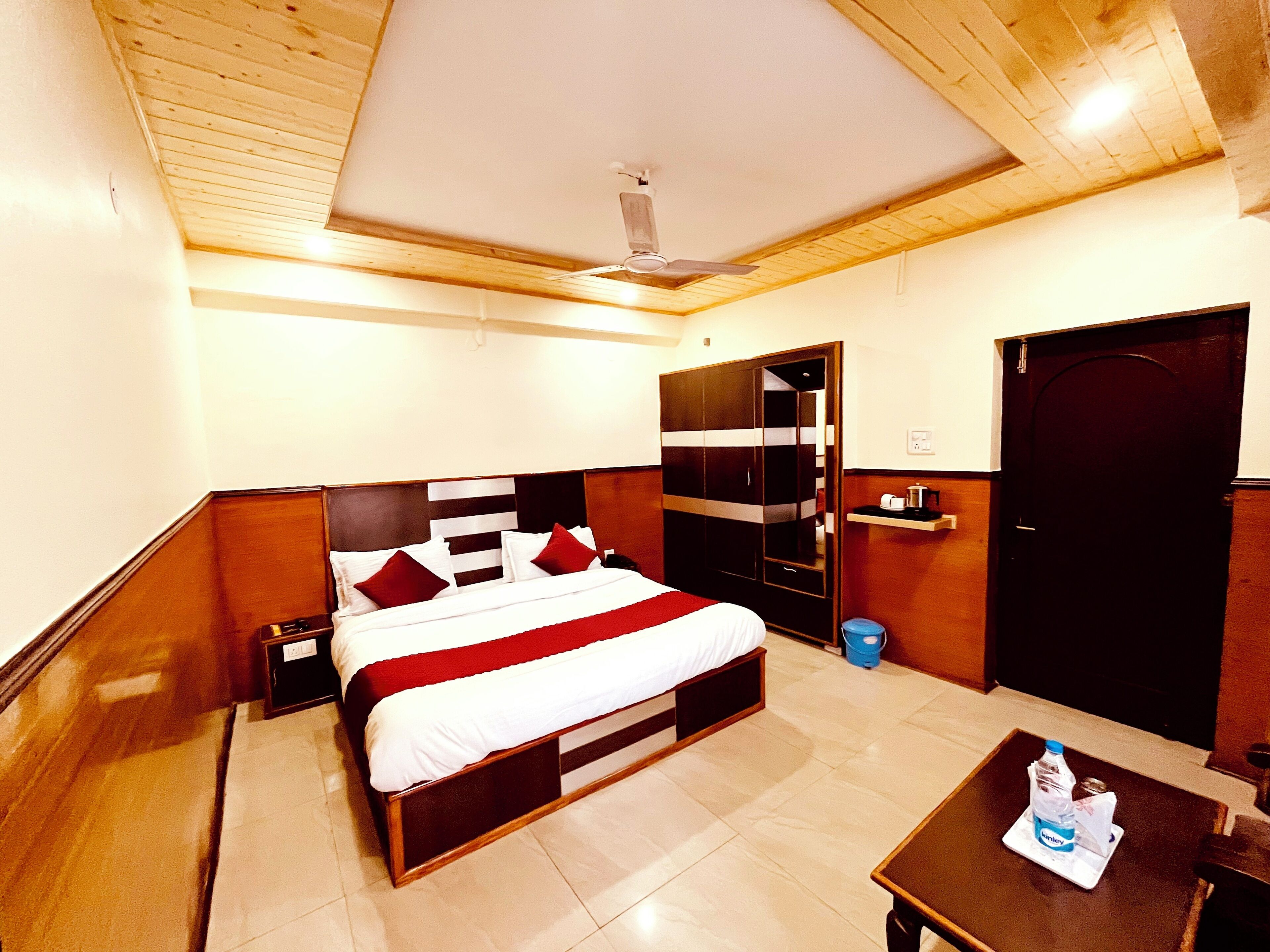 A hotel room with a bed, bedside table, wardrobe, and a door.