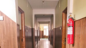 Un couloir aux murs recouverts de lambris en bois, doté d’un sol carrelé et d’un extincteur fixé au mur.