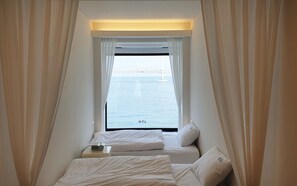 A small, triangular room with two beds and a window overlooking a bridge. - H7L (Busan)