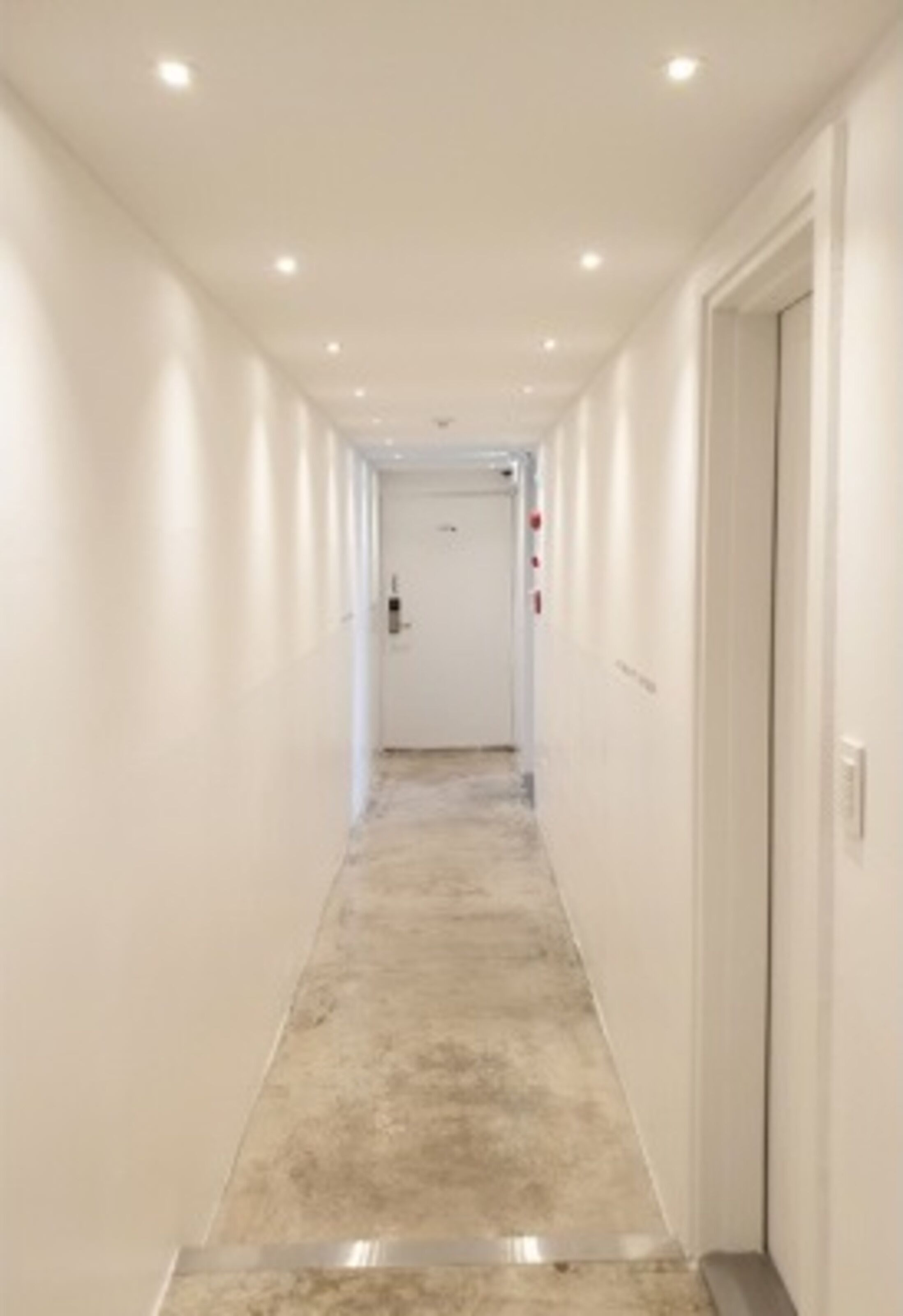 A narrow, well-lit hallway with a tiled floor and white walls.