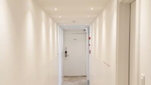 A narrow, well-lit hallway with a tiled floor and white walls.