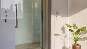 A hotel entrance with a glass door, a potted plant, and a sign reading "HOTEL".