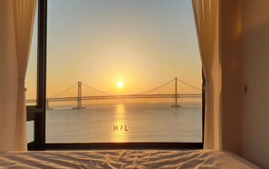A room with a large window overlooking a bridge at sunset. - H7L (Busan)