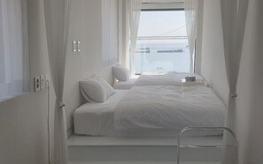 Een hotelkamer met twee bedden, uitzicht op een brug en een raam met gordijnen.