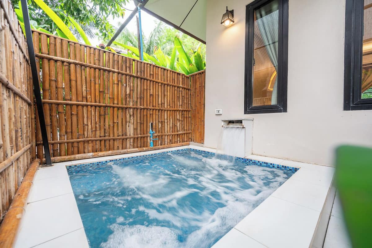 A small indoor pool with a bamboo fence, a tiled floor, and a window with a curtain.