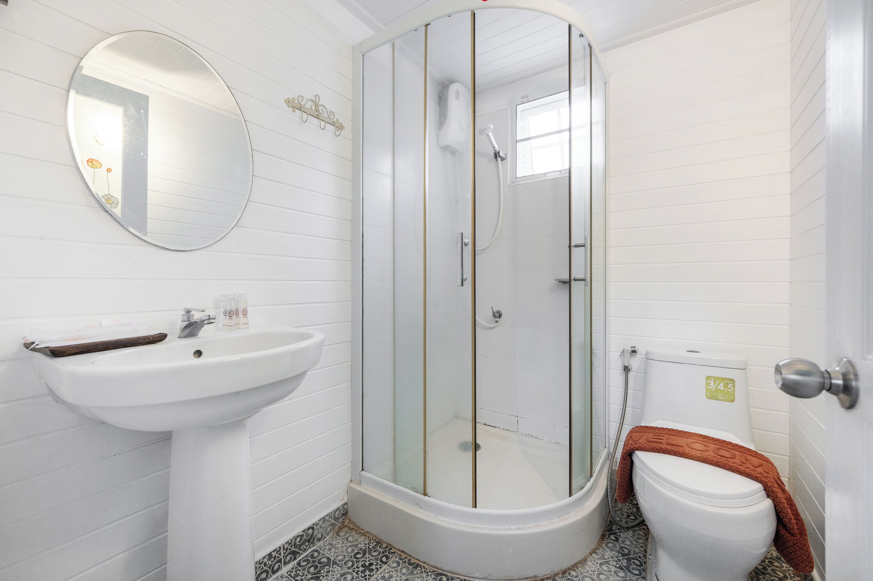 A bathroom with a glass-enclosed shower, a pedestal sink, and a toilet with a towel on it.