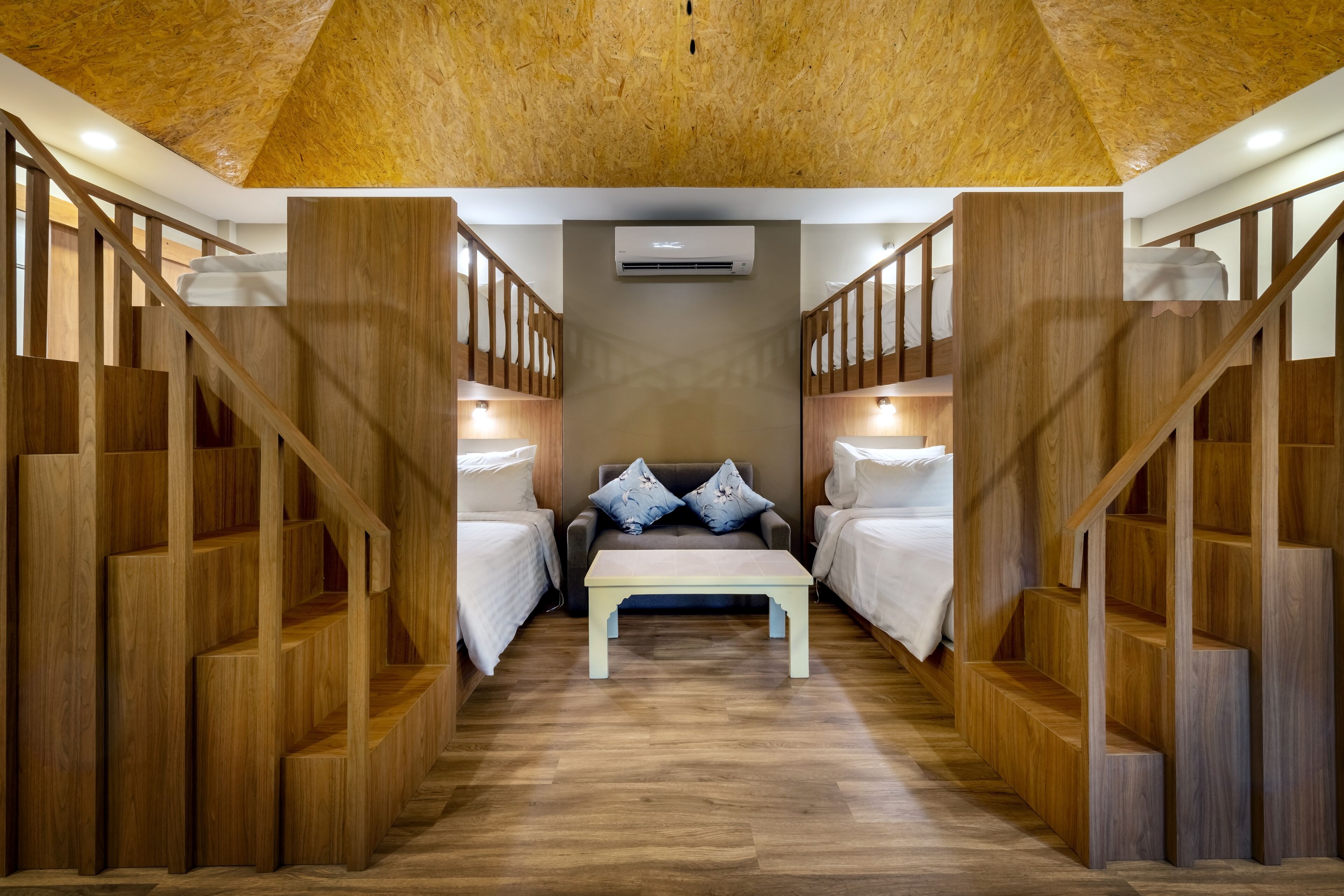 Une chambre d’hôtel avec un escalier en bois, un lit placé au centre et une petite table.