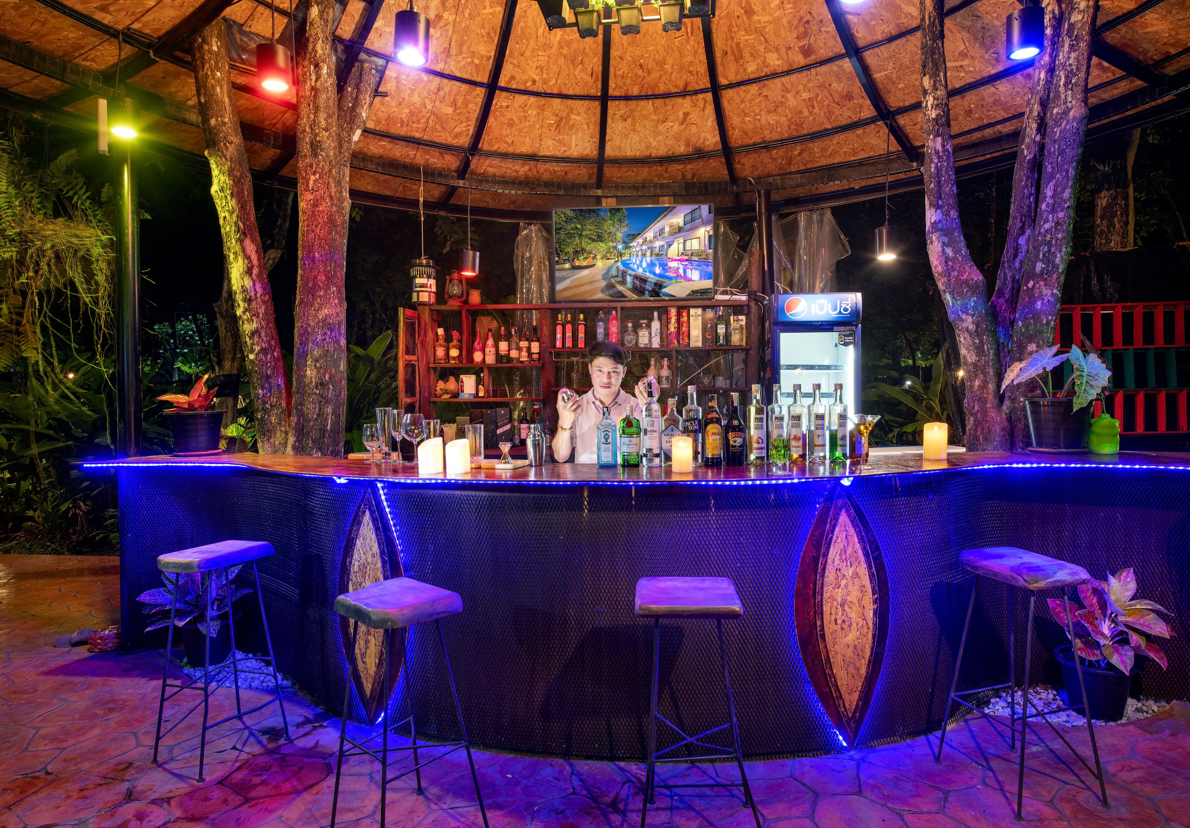 A bar area with a circular design, bar stools, and a display of various bottles and glasses.