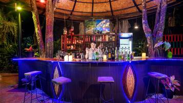 A bar area with a circular design, bar stools, and a display of various bottles and glasses.