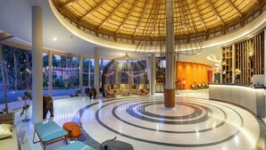 Un'ampia hall con un design circolare centrale, una reception e un'area salotto con vista sull'esterno.