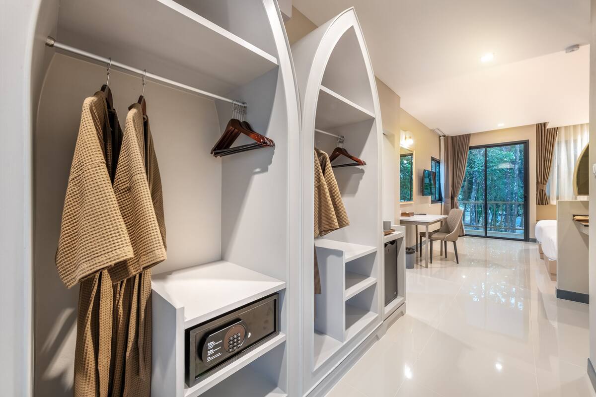 A modern hotel room with a walk-in closet, a dining area, and a large window with a view.