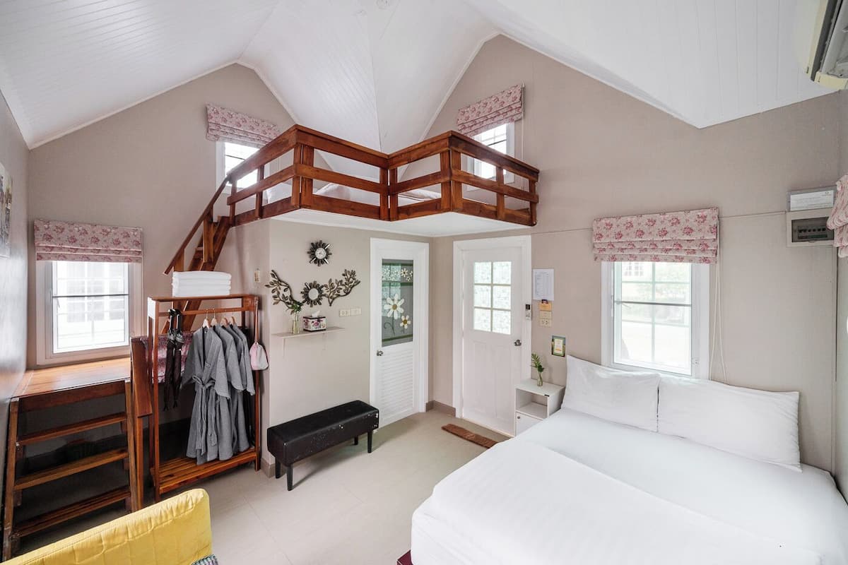 A bedroom with a bunk bed, a desk with a chair, a bench, and a wardrobe.