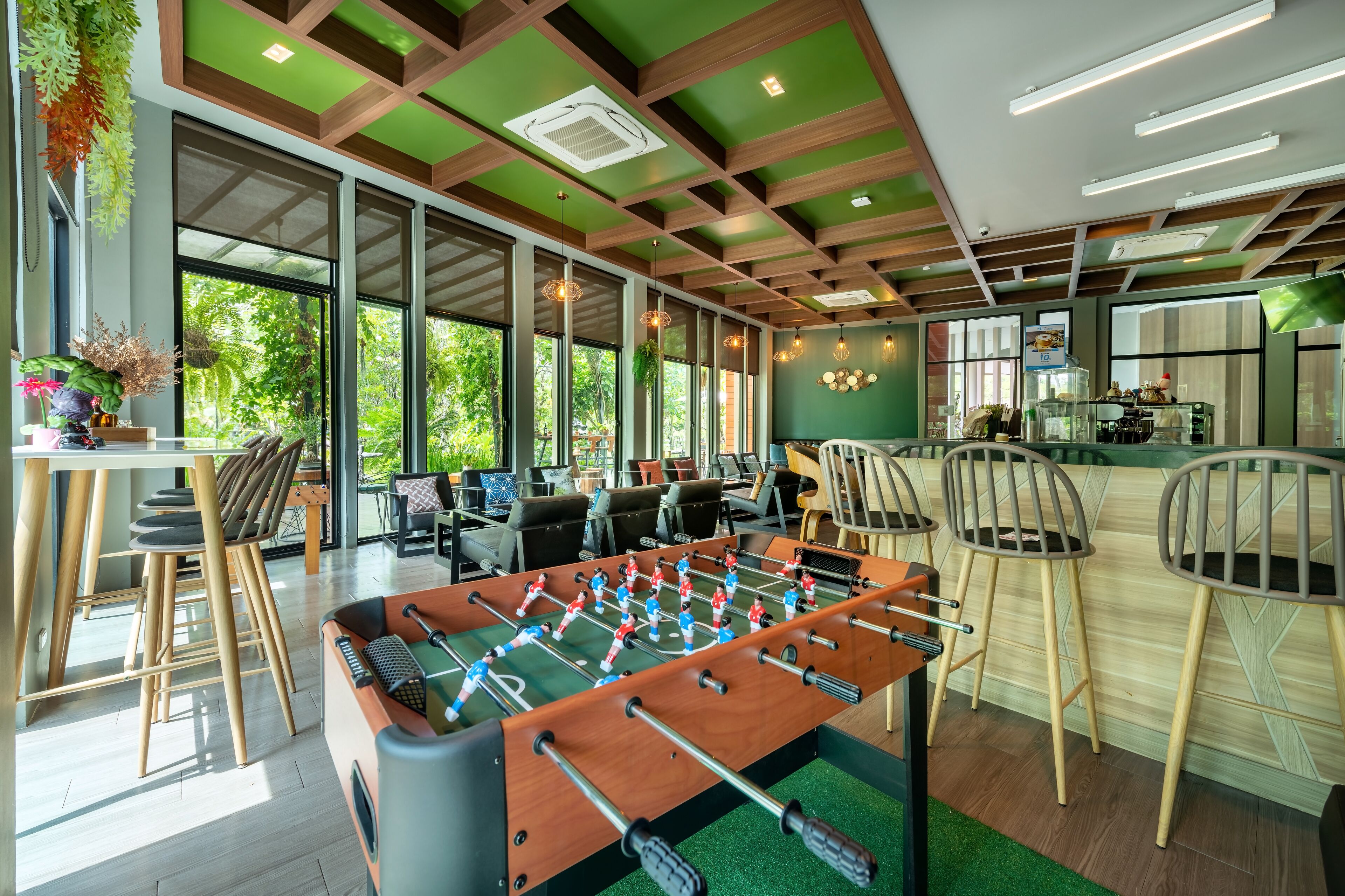 A modern indoor space with a foosball table, seating areas, and large windows providing natural light.