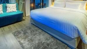 Camera moderna con un letto grande, un'area salotto con cuscini e vista panoramica tramite vetrate.