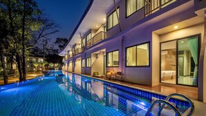 Un hotel con piscina, numerosi balconi e ampie finestre.