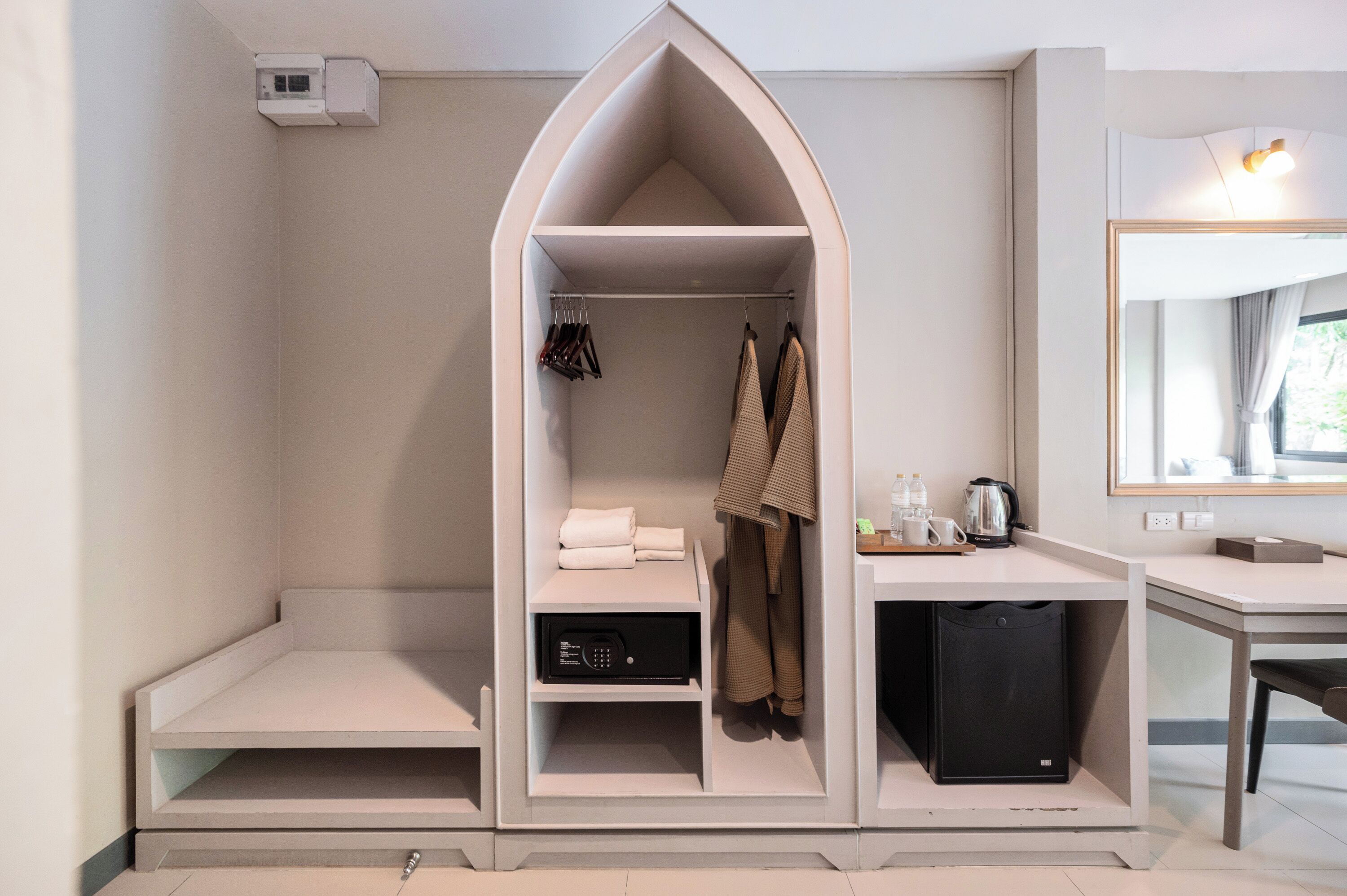 Ein Schlafzimmer mit Einbauschrank, Nachttisch mit Lampe und Spiegel.