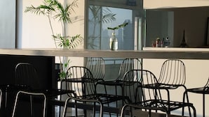 Een modern interieur met een glazen tafel, zwarte metalen stoelen en een potplant.