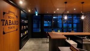 A modern hotel interior with a wooden reception desk, a bar area, and large windows offering views of the cityscape. - Hotel Tabard Tokyo (Tokyo)