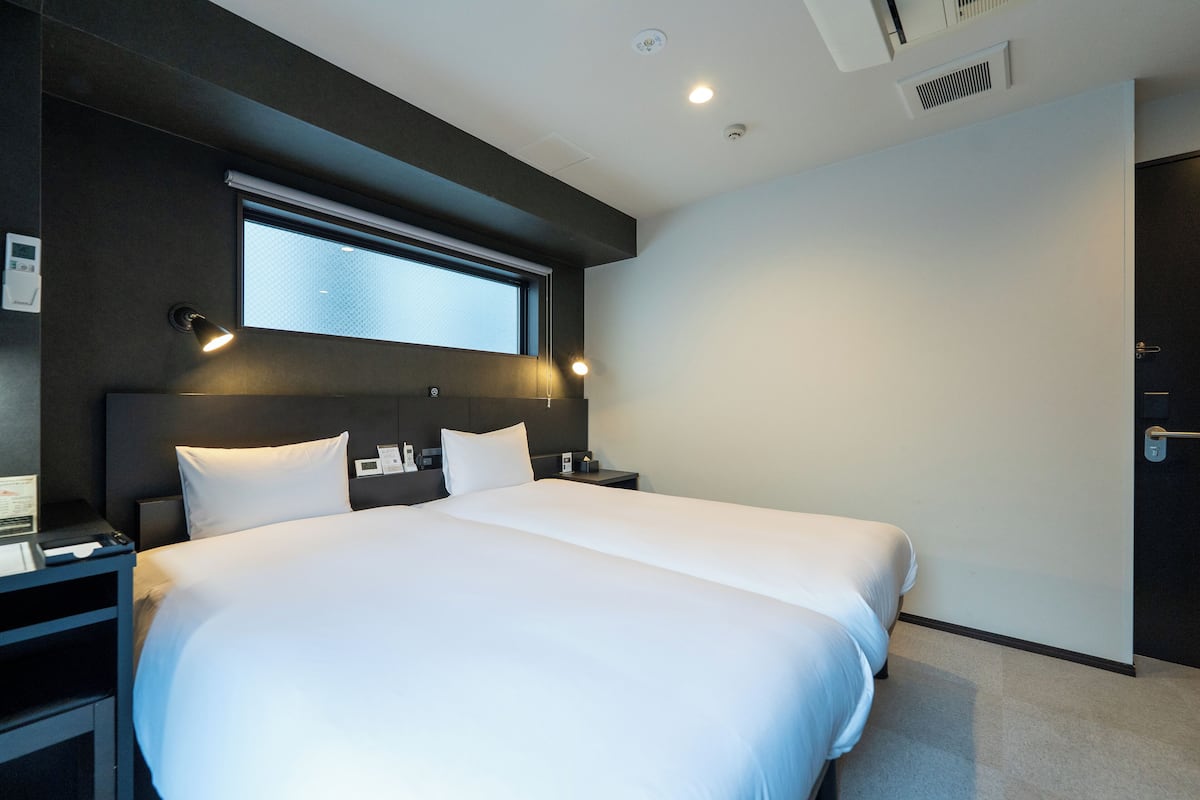 Een moderne hotelkamer met een groot bed, een nachtkastje en een raam met zonwering.