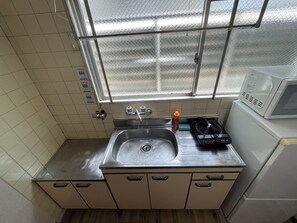 A small kitchen with a sink, a microwave, and a window above the sink.