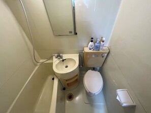 A bathroom with a sink, toilet, and hand soap dispensers.