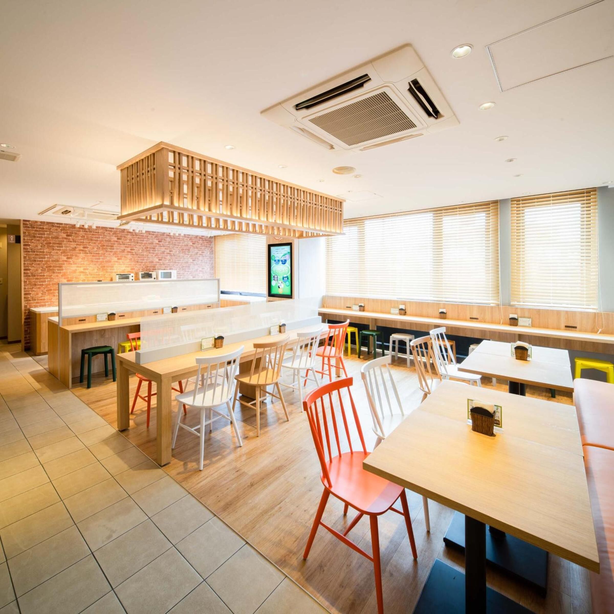 Un café moderne avec des tables et des chaises en bois, un mur en briques et de grandes fenêtres.