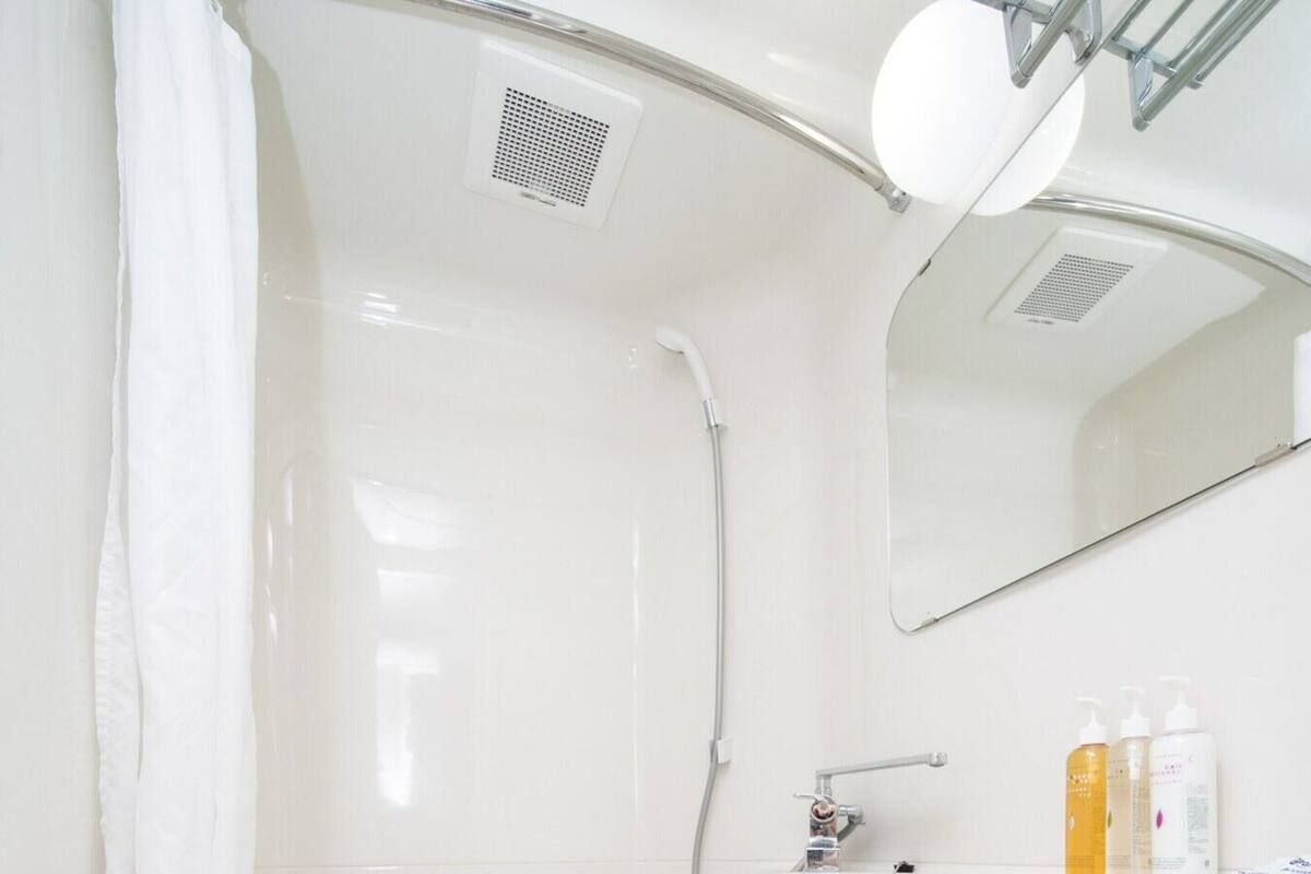 A modern bathroom with a white toilet, a shower, and a sink with toiletries.