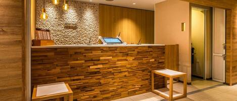 A reception area with a wooden wall, a reception desk, and two wooden stools.