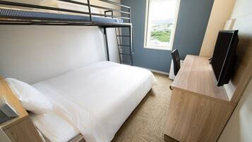 Et hotelværelse med køjeseng, skrivebord med fladskærms-tv og vindue med udsigt over byen.