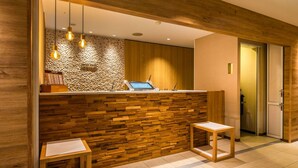 A reception area with a wooden wall, a reception desk, and two wooden stools.