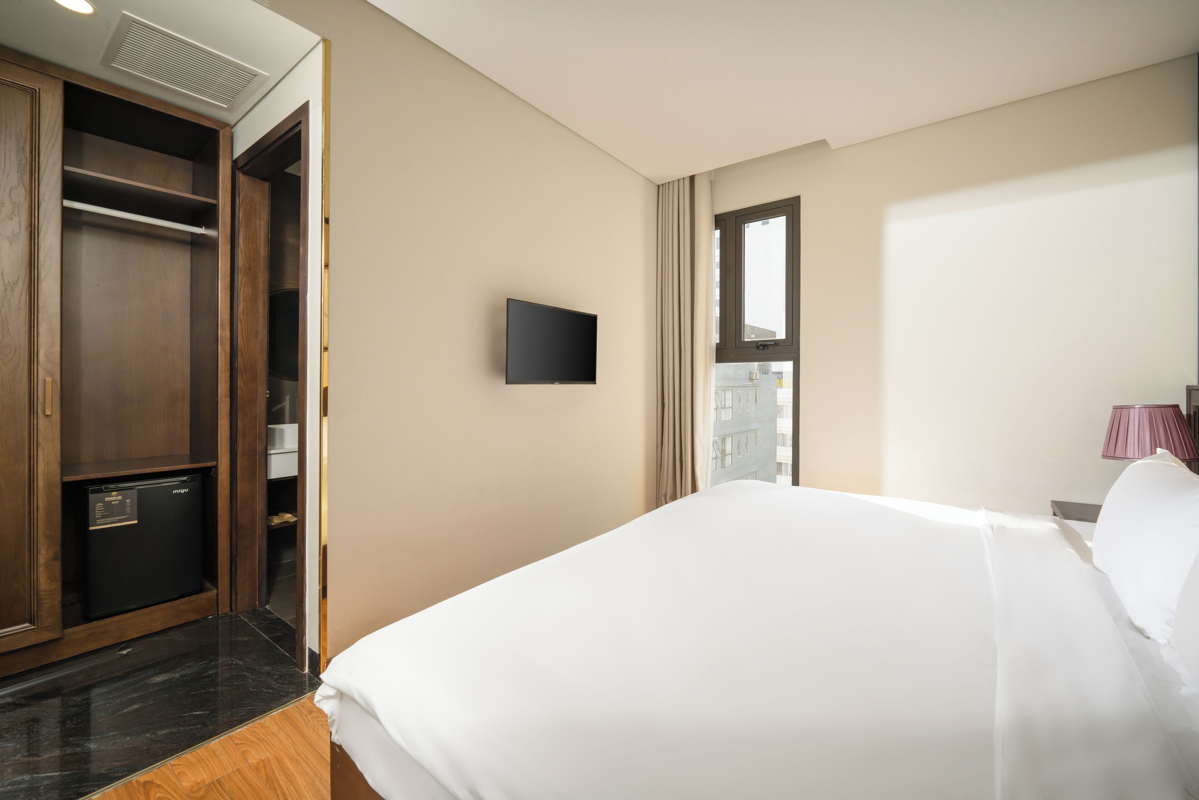A hotel room with a bed, a wardrobe, a television, and a window.