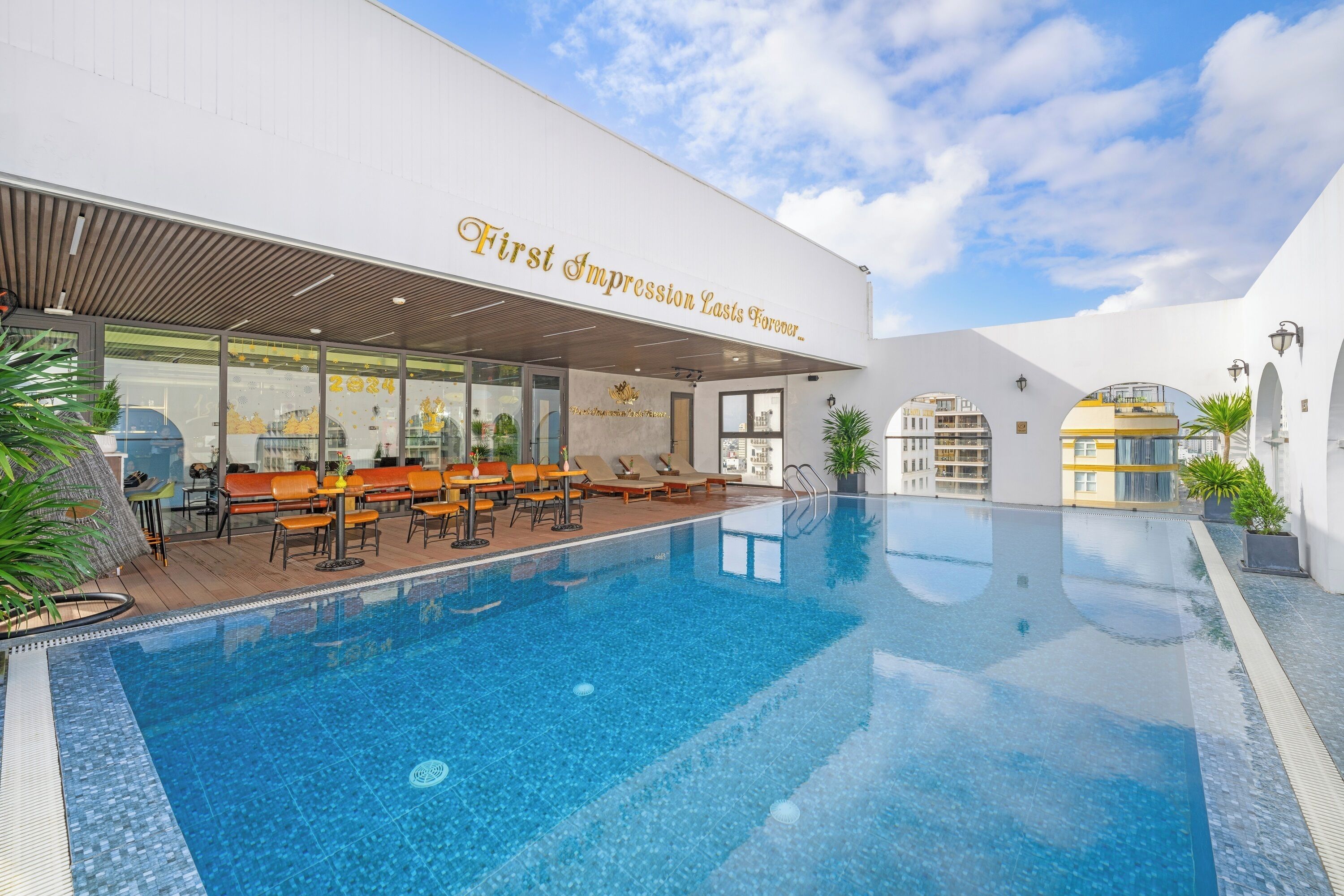 Un hôtel moderne doté d’une piscine, d’un espace extérieur aménagé et offrant une vue sur un ciel dégagé.