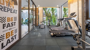 Une salle de sport équipée de tapis de course, de vélos d’appartement et d’appareils de musculation.