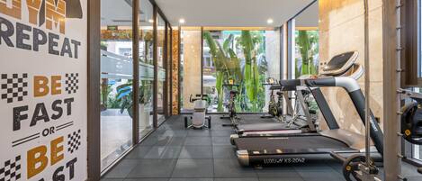 Une salle de sport équipée de tapis de course, de vélos d’appartement et d’appareils de musculation.
