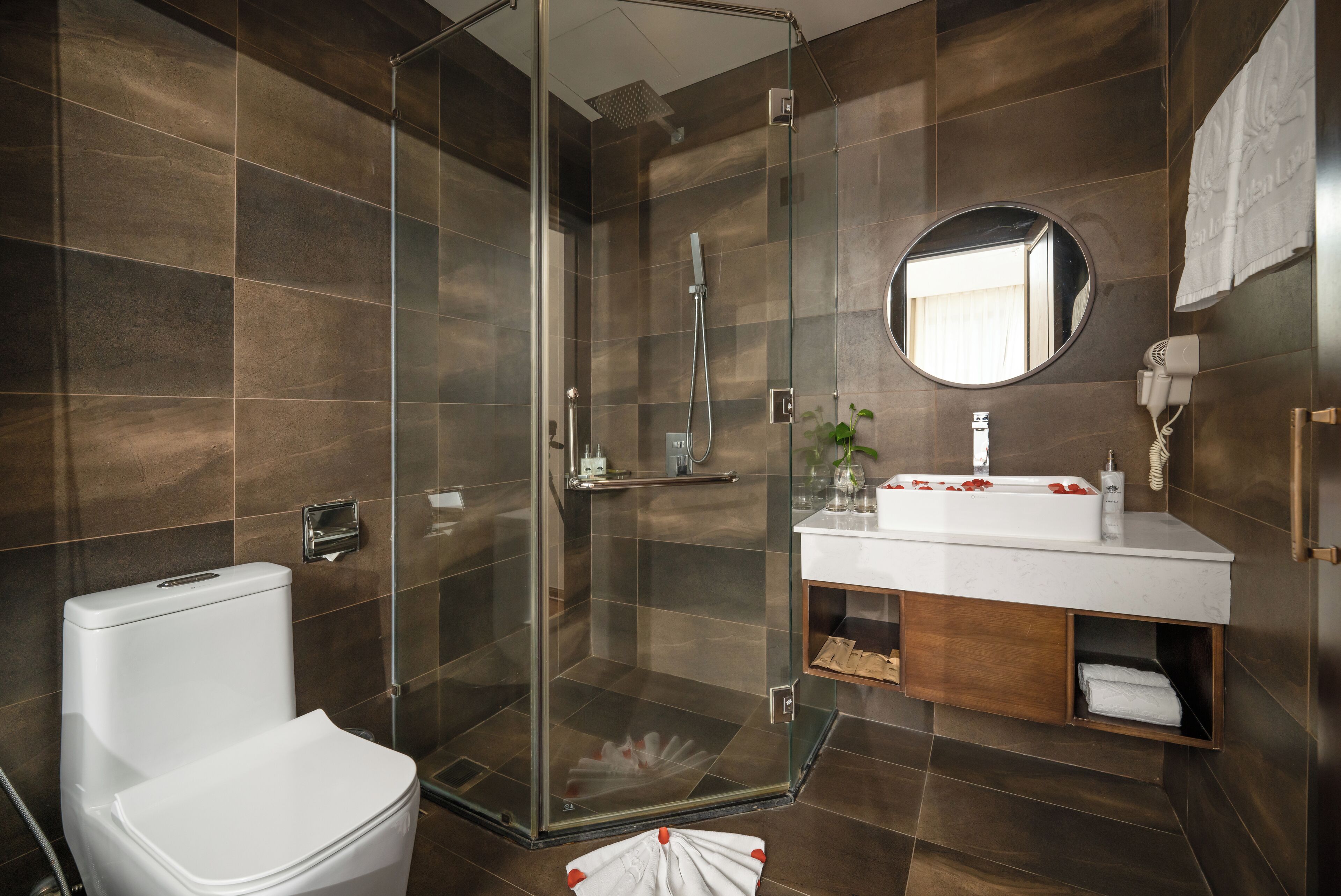 Een moderne badkamer met een glazen douchecabine, een wit toilet en een wastafel met spiegel.