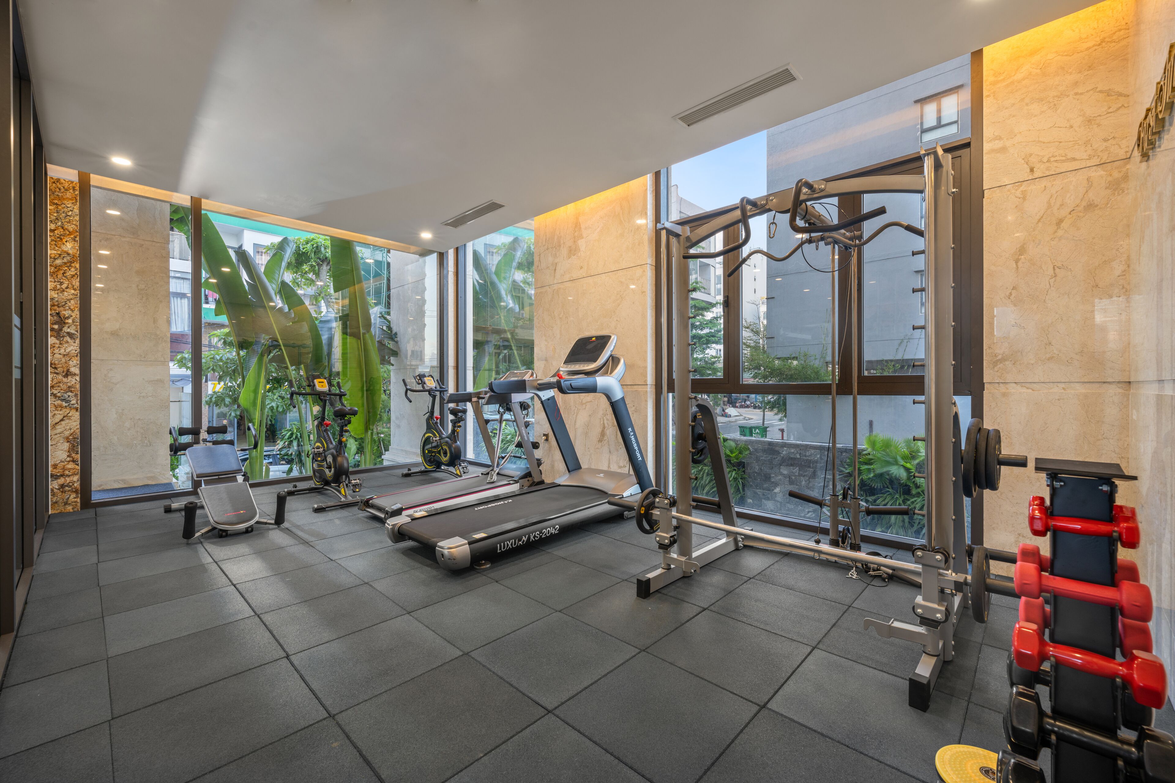 A modern gym with a treadmill, stationary bikes, and weight machines.
