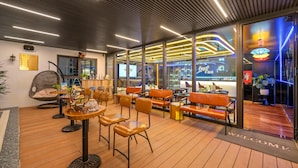 A modern lounge area with wooden flooring, leather seating, and a bar visible through glass doors. - Golden Lotus Hotel Da Nang (Da Nang)