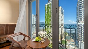 A balcony with a view of tall buildings and a table with a vase of flowers. - Golden Lotus Hotel Da Nang (Da Nang)