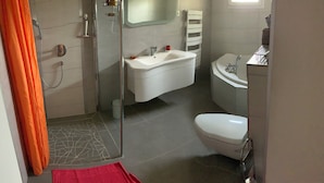 A bathroom with a shower, sink, toilet, and a towel rack.