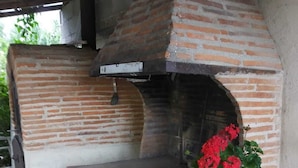 A brick-built outdoor oven with a bench and a potted plant.