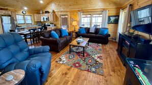 Un interior acogedor de cabaña con sala de estar, comedor, cocina y televisor.