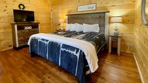 Un dormitorio tipo cabaña de madera con una cama, un televisor y un letrero que dice 'love'.