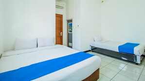 Une chambre d’hôtel avec deux lits, une porte en bois, un appareil de climatisation et un petit tableau accroché au mur.